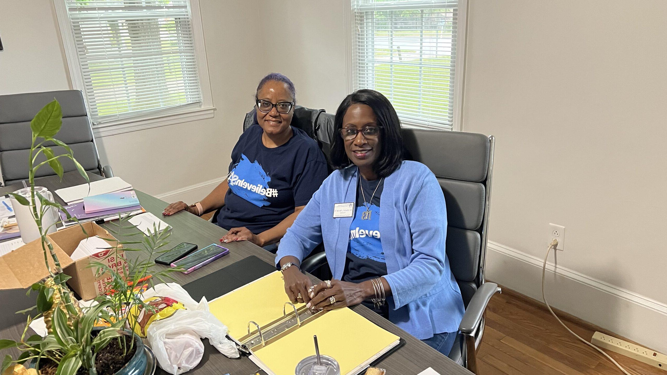 two member of the SAU NAA sitting at a table, looking at the camera in support of SAU